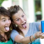 Teenage girls photographing themselves with a mobile phone.